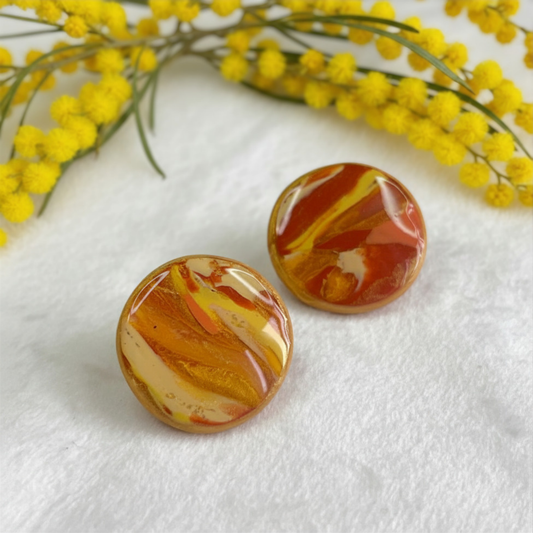 Marbled orange and yellow circular objects on a white surface with yellow flowers in the background.