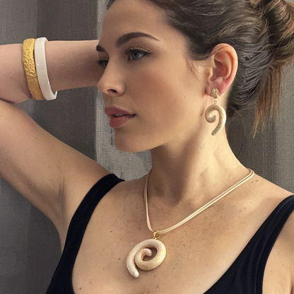 Woman wearing a spiral necklace and earrings against a neutral background