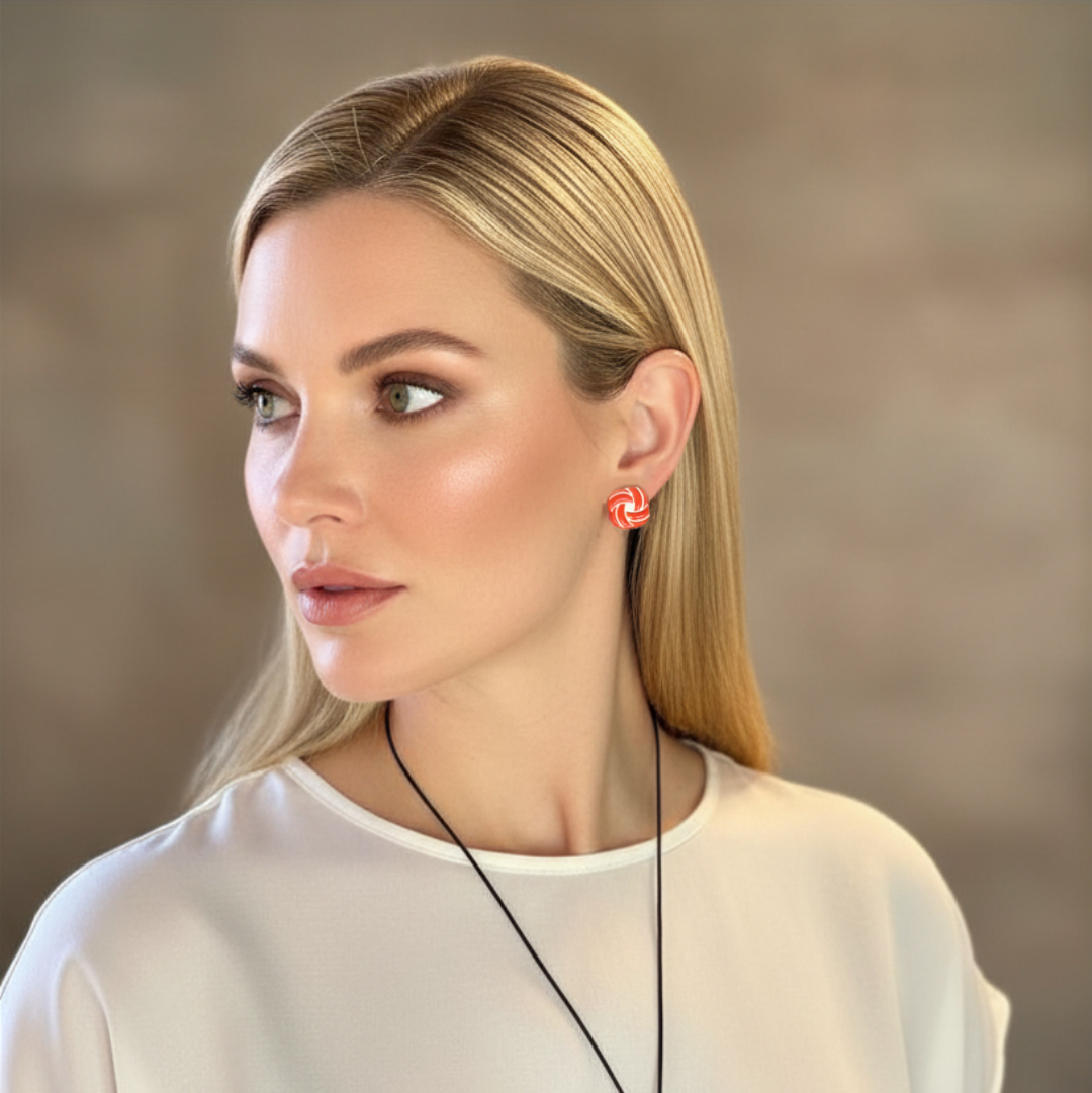 Woman wearing a necklace with red earrings against a neutral background