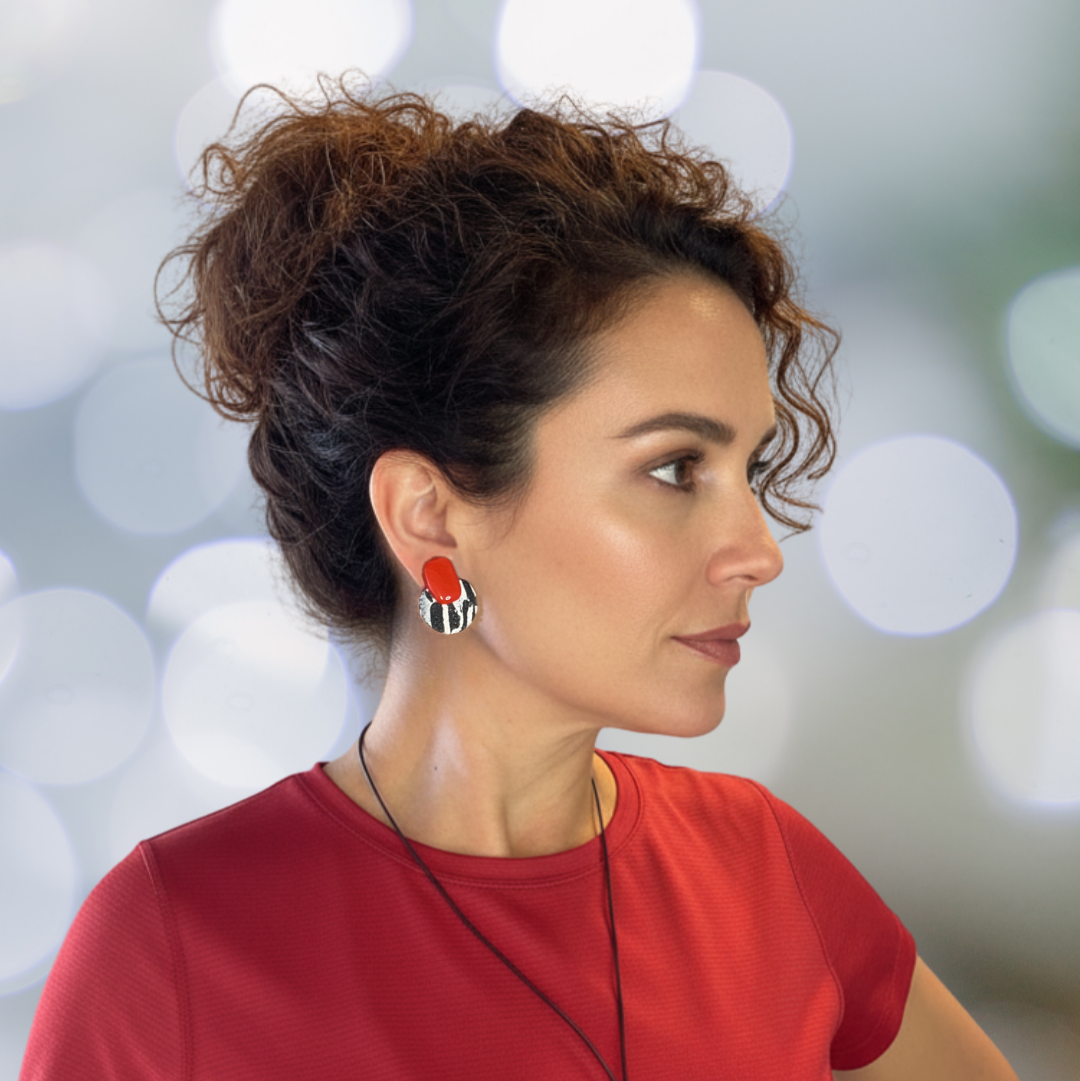 Woman wearing a red shirt with a necklace and earrings against a blurred background